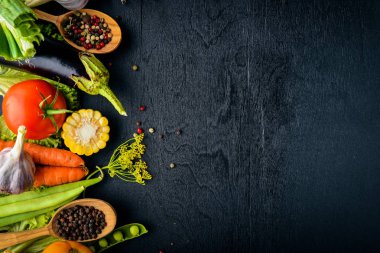 Büyük bir seçim çiğ taze sebze ve baharat. Siyah ahşap arka plan üzerinde. Üstten Görünüm. Metniniz için boş alan.
