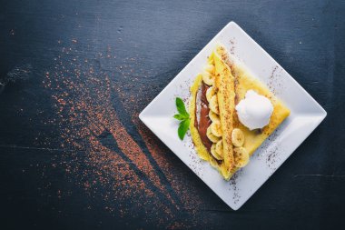 Çikolata ve muz krep. Tatlı. Ahşap bir arka plan üzerinde. Üstten Görünüm. Metniniz için boş alan.