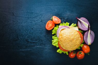 Peynir, et, domates ve soğan ve otlar ile hamburger. Ahşap arka plan üzerinde. Üstten Görünüm. Boş alan.