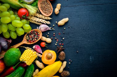 Çiğ sebze, meyve ve baharat bir siyah ahşap yüzey üzerinde büyük bir seçim. Metniniz için boş alan. Üstten Görünüm.