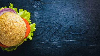 Peynir, et, domates ve soğan ve otlar ile hamburger. Ahşap arka plan üzerinde. Üstten Görünüm. Boş alan.
