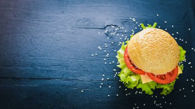 Peynir, et, domates ve soğan ve otlar ile hamburger. Ahşap arka plan üzerinde. Üstten Görünüm. Boş alan.