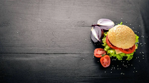 Peynir, et, domates ve soğan ve otlar ile hamburger. Ahşap arka plan üzerinde. Üstten Görünüm. Boş alan.