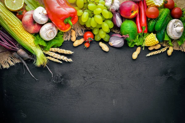 Çiğ sebze ve meyveler siyah ahşap bir masa üzerinde geniş yelpazesi. Metniniz için boş alan. Üstten Görünüm.