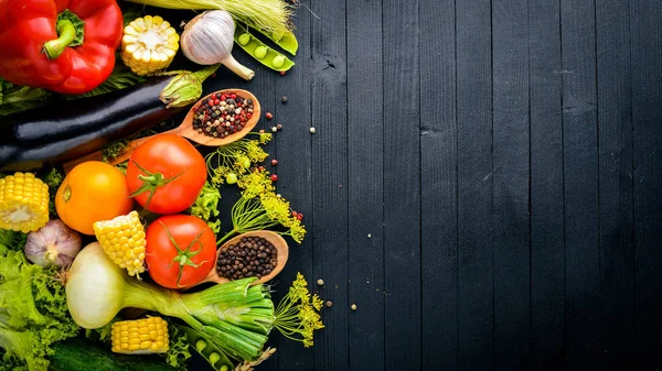 Un large choix de légumes frais crus et d'épices. Sur un fond en bois noir. Vue de dessus. Espace libre pour votre texte . — Photo