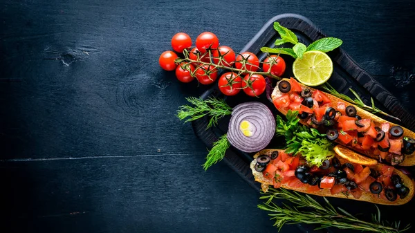 Bruschetta domates, zeytin, otlar ve parmesan peyniri ekmeğin. Soğuk aperatifler. İtalyan mutfağı. Ahşap arka plan üzerinde.