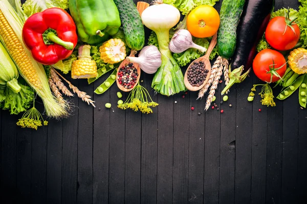 Büyük bir seçim çiğ taze sebze ve baharat. Siyah ahşap arka plan üzerinde. Üstten Görünüm. Metniniz için boş alan.