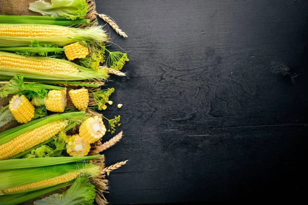 Mısır. Çiğ sebze siyah bir ahşap zemin üzerine. Üstten Görünüm. Metniniz için boş alan.