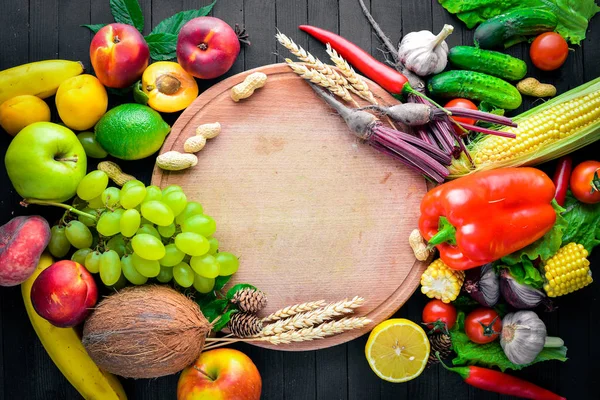 Çiğ sebze ve meyveler siyah ahşap bir masa üzerinde geniş yelpazesi. Metniniz için boş alan. Üstten Görünüm.