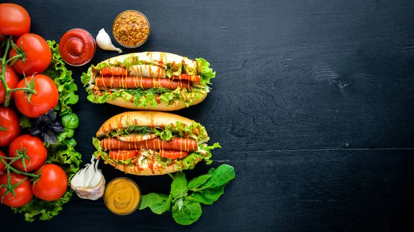 Hot dog with grilled sausage, mustard and ketchup, onions and greens on Wooden background. Top view. Free space. — Stock Photo, Image