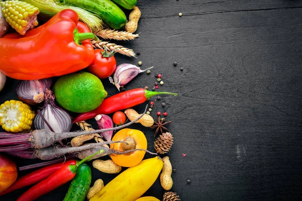 Çiğ sebze, meyve ve baharat bir siyah ahşap yüzey üzerinde büyük bir seçim. Metniniz için boş alan. Üstten Görünüm.