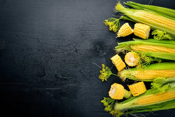 Mais. Rohes Gemüse auf schwarzem Holzgrund. Ansicht von oben. Freiraum für Ihren Text. — Stockfoto