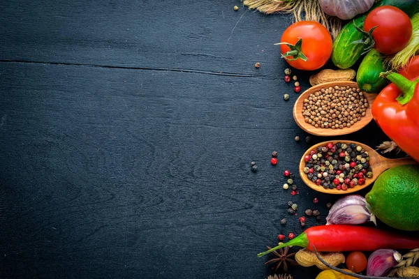 Eine große Auswahl an rohem Gemüse, Obst und Gewürzen auf einer schwarzen Holzoberfläche. Freiraum für Ihren Text. Ansicht von oben. — Stockfoto