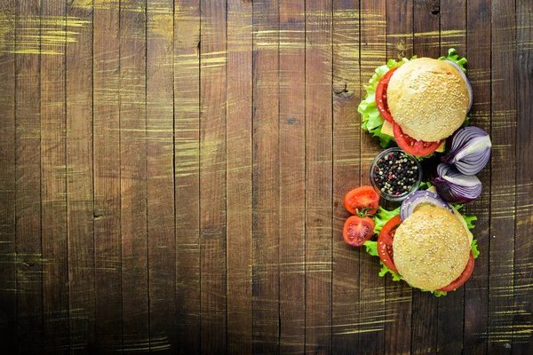 Гамбургер з сиром, м'ясом, помідорами та цибулею та травами. На дерев'яному тлі. Вид зверху. Вільний простір . — стокове фото