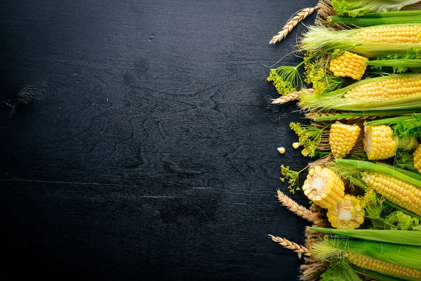 Mısır. Çiğ sebze siyah bir ahşap zemin üzerine. Üstten Görünüm. Metniniz için boş alan.