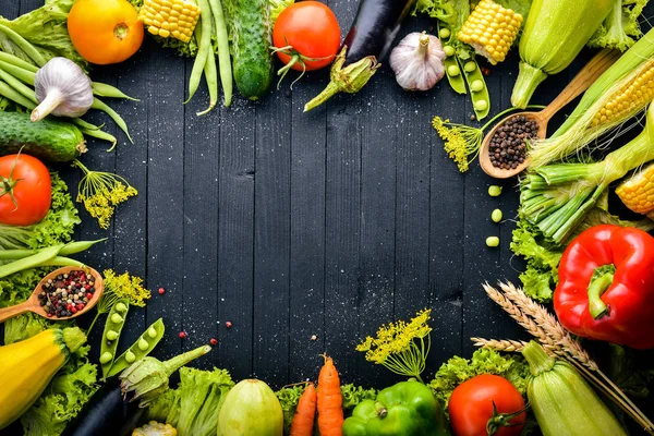 Büyük bir seçim çiğ taze sebze ve baharat. Siyah ahşap arka plan üzerinde. Üstten Görünüm. Metniniz için boş alan.