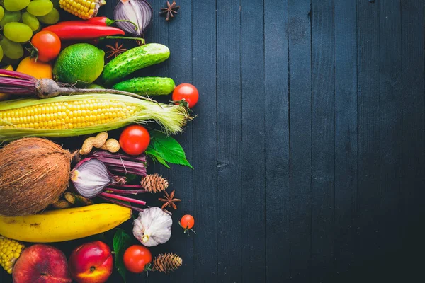 Çiğ sebze ve meyveler siyah ahşap bir masa üzerinde geniş yelpazesi. Metniniz için boş alan. Üstten Görünüm.