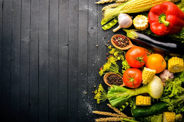 Una gran selección de verduras frescas crudas y especias. Sobre un fondo de madera negro. Vista superior. Espacio libre para tu texto . — Foto de Stock