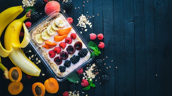 Taze meyveler ve meyve yulaf ezmesi. Sağlıklı bir diyet yemek. Öğle Yemeği boks. Ahşap bir arka plan üzerinde. Üstten Görünüm. Metin için boş alan.