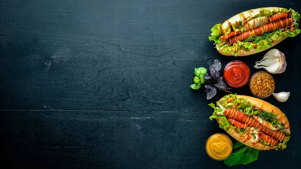 Sosis ızgara sosis, hardal ve ketçap, soğan ve Yeşiller ahşap arka plan üzerinde. Üstten Görünüm. Boş alan.