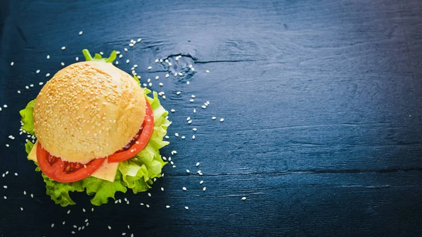 Peynir, et, domates ve soğan ve otlar ile hamburger. Ahşap arka plan üzerinde. Üstten Görünüm. Boş alan.