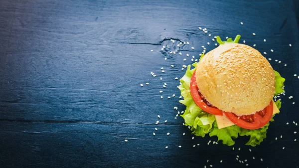 Peynir, et, domates ve soğan ve otlar ile hamburger. Ahşap arka plan üzerinde. Üstten Görünüm. Boş alan.