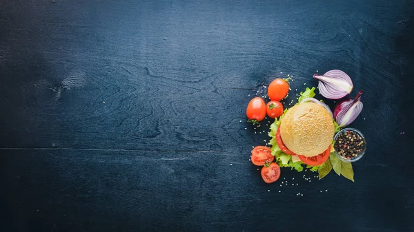 Peynir, et, domates ve soğan ve otlar ile hamburger. Ahşap arka plan üzerinde. Üstten Görünüm. Boş alan.