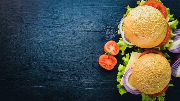 Peynir, et, domates ve soğan ve otlar ile hamburger. Ahşap arka plan üzerinde. Üstten Görünüm. Boş alan.