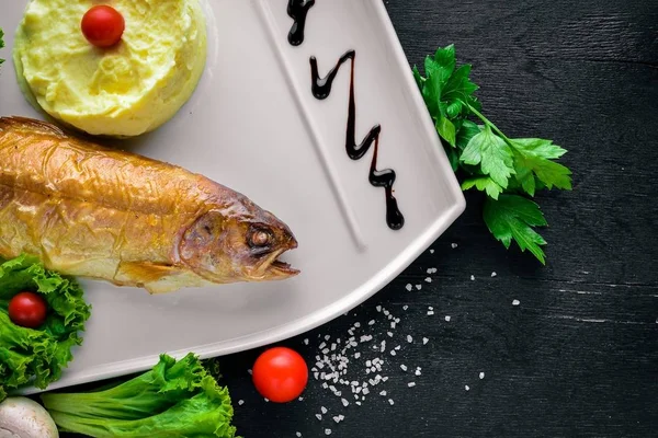 Paistettua kalaa sibas perunamuusia ja vihanneksia. Puupohjalla. Huippunäkymä. Vapaa tila tekstille . — kuvapankkivalokuva