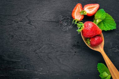 Çilek bir tahta kaşık üzerinde. Ahşap bir arka plan üzerinde. Üstten Görünüm. Metin için boş alan.