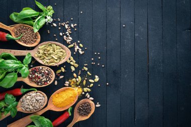 Çeşitli baharatlar kaşık taş masada. Ahşap bir gemide. Üstten Görünüm. Metniniz için boş alan.