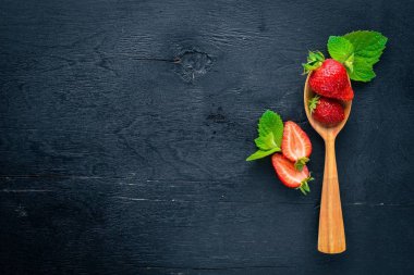 Çilek bir tahta kaşık üzerinde. Ahşap bir arka plan üzerinde. Üstten Görünüm. Metin için boş alan.