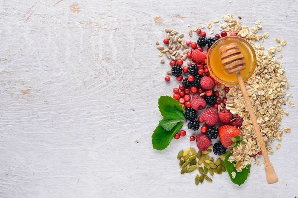 Sağlıklı gıda. Taze yabani çilek, bakır, fındık, yulaf ezmesi, Kuruyemiş ve tohumlar. Ahşap bir arka plan üzerinde. Üstten Görünüm. Metin için boş alan.