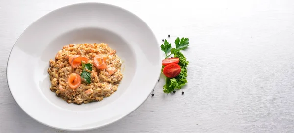 Risotto met zalm en crème saus. Op een houten achtergrond. Bovenaanzicht. Vrije ruimte. — Stockfoto