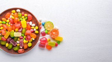 Renkli şeker, tatlılar ve lolipop. Beyaz ahşap zemin üzerinde. Üstten Görünüm. Boş alan.