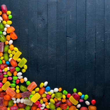 Renkli şeker, tatlılar ve lolipop. Siyah ahşap arka plan üzerinde. Üstten Görünüm. Boş alan.
