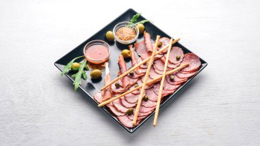 Ketçap ve hardal ile bir tabakta et dilimleri. Sucuk ve pastırma. Ahşap bir arka plan üzerinde. Üstten Görünüm. Boş alan.