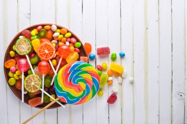 Renkli şeker, tatlılar ve lolipop. Beyaz ahşap zemin üzerinde. Üstten Görünüm. Boş alan.
