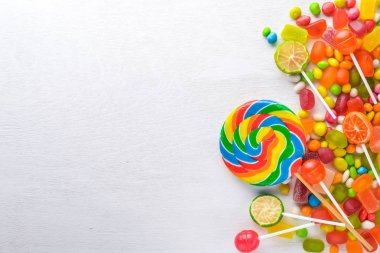 Renkli şeker, tatlılar ve lolipop. Beyaz ahşap zemin üzerinde. Üstten Görünüm. Boş alan.