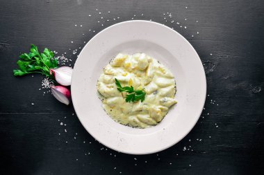 Patates peynir sosu altında gelen hamur tatlısı. Ahşap bir arka plan üzerinde. Üstten Görünüm. Boş alan.