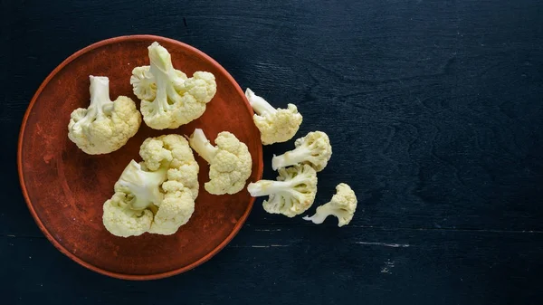 Cauliflower. On a black wooden background. Top view. Free space.