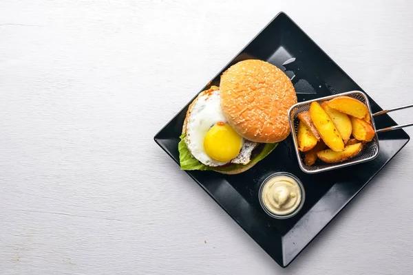 Breakfast. French fries and burger with meat and egg. On a wooden background. Top view. Free space.