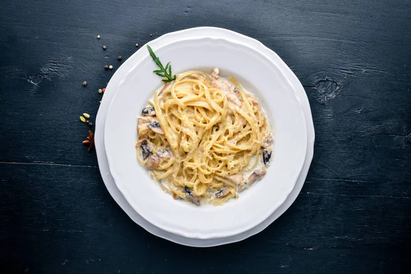 チキンとキノコのパスタ。イタリア料理。木製の背景。平面図です。テキスト用の空き容量. — ストック写真