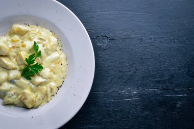 Patates peynir sosu altında gelen hamur tatlısı. Ahşap bir arka plan üzerinde. Üstten Görünüm. Boş alan.