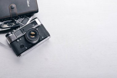 Kamera, dizüstü bilgisayar, göz mercekleri ve kalem ile Office çalışma alanı. Bir ahşap yüzeye. Üstten Görünüm. Metniniz için boş alan.