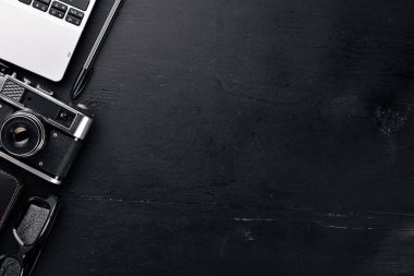 Kamera, dizüstü bilgisayar, göz mercekleri ve kalem ile Office çalışma alanı. Bir ahşap yüzeye. Üstten Görünüm. Metniniz için boş alan.