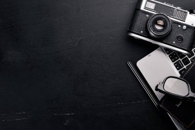 Kamera, dizüstü bilgisayar, göz mercekleri ve kalem ile Office çalışma alanı. Bir ahşap yüzeye. Üstten Görünüm. Metniniz için boş alan.