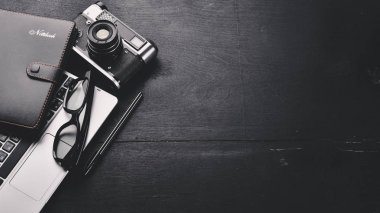 Kamera, dizüstü bilgisayar, göz mercekleri ve kalem ile Office çalışma alanı. Bir ahşap yüzeye. Üstten Görünüm. Metniniz için boş alan.