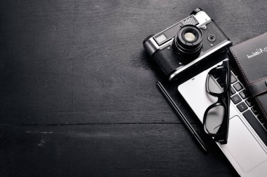 Kamera, dizüstü bilgisayar, göz mercekleri ve kalem ile Office çalışma alanı. Bir ahşap yüzeye. Üstten Görünüm. Metniniz için boş alan.