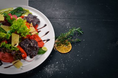 Biftek salata ve taze sebze. Bir ahşap yüzeye. Üstten Görünüm. Metniniz için boş alan.